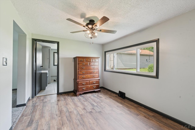 605 Oak St, Hudson, MI 49247 - unfurnished bedroom with wood finished floors, a textured ceiling, a ceiling fan, and connected bathroom