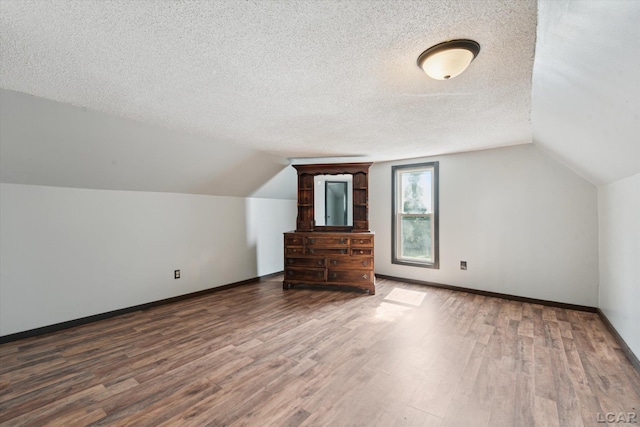 605 Oak St, Hudson, MI 49247 - additional living space with wood finished floors, vaulted ceiling, and a textured ceiling