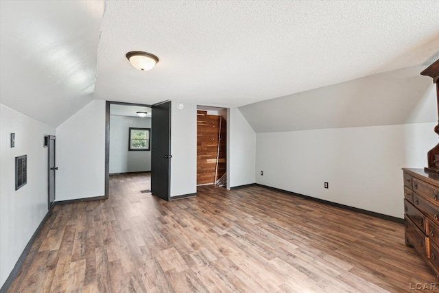 605 Oak St, Hudson, MI 49247 - bonus room featuring wood finished floors, vaulted ceiling, and a textured ceiling