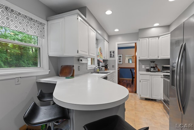 1043 Orchard Rd, Adrian, MI 49221 - kitchen featuring stainless steel refrigerator with ice dispenser, a peninsula, light countertops, a breakfast bar area, and white cabinets