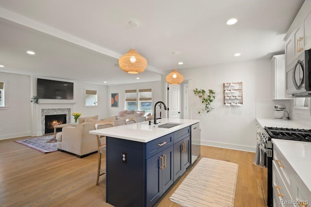 423 N Altadena Ave, Royal Oak, MI 48067 - kitchen with stainless steel appliances, a breakfast bar area, white cabinets, light countertops, and a lit fireplace