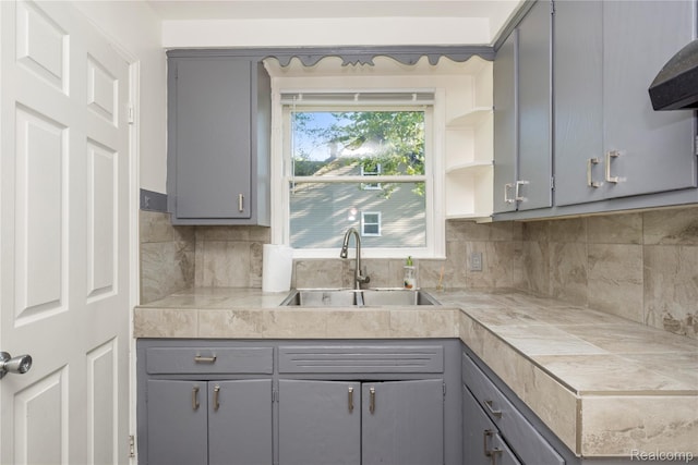 20258 Caldwell St, Detroit, MI 48234 - kitchen featuring gray cabinets, range hood, and decorative backsplash