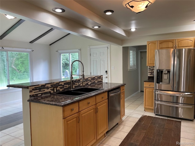 21150 E Chigwidden St, Northville, MI 48167 - kitchen featuring appliances with stainless steel finishes, decorative backsplash, dark stone countertops, a kitchen island with sink, and lofted ceiling