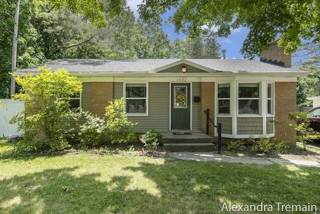 1602 4th St NW, Grand Rapids, MI 49504 - view of front of property with a front yard, a chimney, roof with shingles, and brick siding