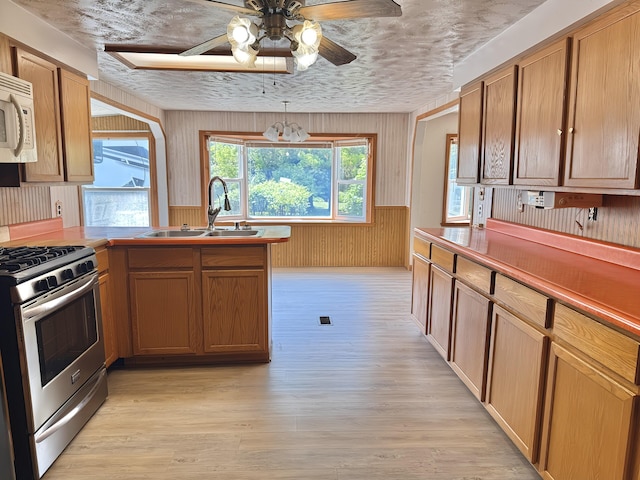 801 S 1st St, Buckley, MI 49620 - kitchen featuring stainless steel gas range, white microwave, ceiling fan, light wood-style floors, and a peninsula