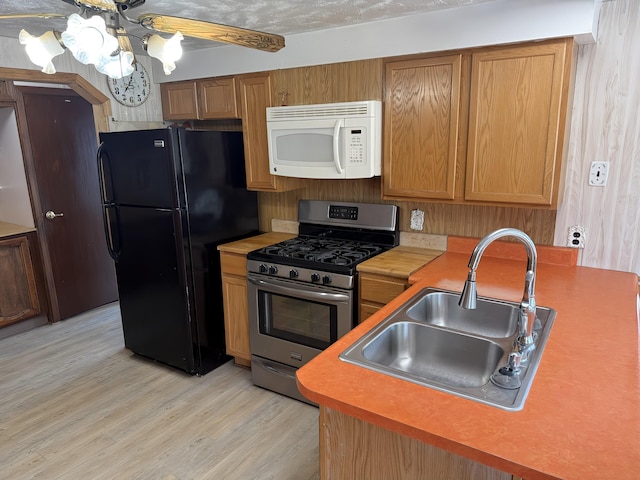 801 S 1st St, Buckley, MI 49620 - kitchen featuring white microwave, stainless steel gas stove, freestanding refrigerator, light wood-style floors, and a chandelier