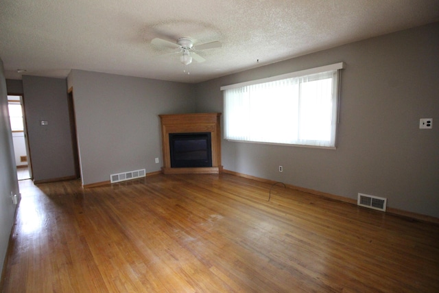 25652 Chernick St, Taylor, MI 48180 - unfurnished living room featuring a ceiling fan, healthy amount of natural light, light wood finished floors, a glass covered fireplace, and a textured ceiling