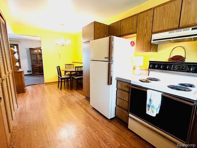 11638 Alois St, Livonia, MI 48150 - kitchen featuring white appliances, under cabinet range hood, a chandelier, and light wood finished floors