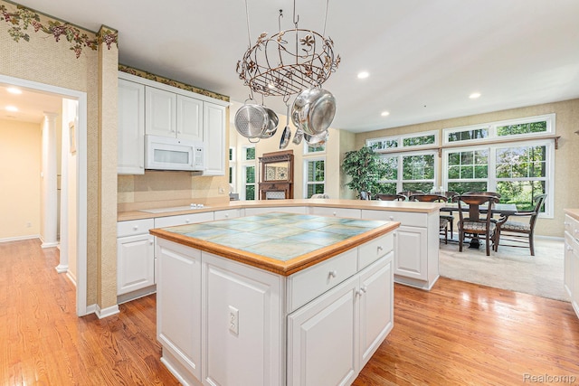 6155 Carey Rd, Commerce Twp, MI 48382 - kitchen featuring white microwave, tile counters, light wood-type flooring, white cabinets, and recessed lighting