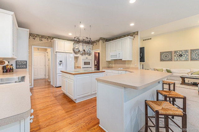 6155 Carey Rd, Commerce Twp, MI 48382 - kitchen featuring white appliances, a kitchen bar, light wood-style floors, white cabinets, and recessed lighting