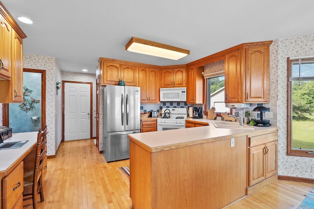 64670 Windrose Way, Lawton, MI 49065 - kitchen featuring white appliances, wallpapered walls, light wood-style flooring, light countertops, and a peninsula