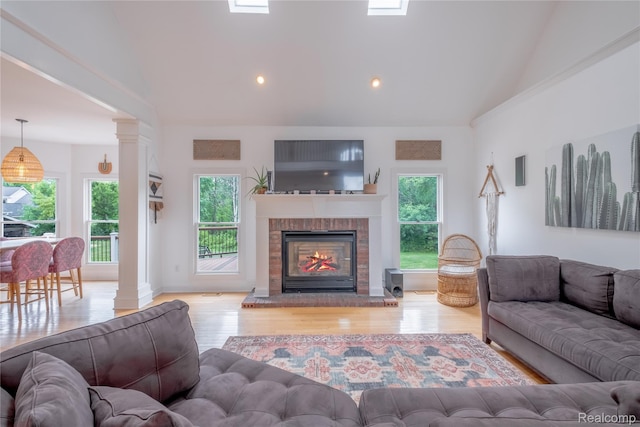 12462 Lillie Rd, Byron, MI 48418 - living area with lofted ceiling, healthy amount of natural light, wood finished floors, a fireplace, and decorative columns