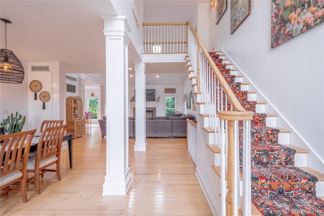 12462 Lillie Rd, Byron, MI 48418 - staircase with ornate columns, healthy amount of natural light, wood finished floors, a fireplace, and a high ceiling