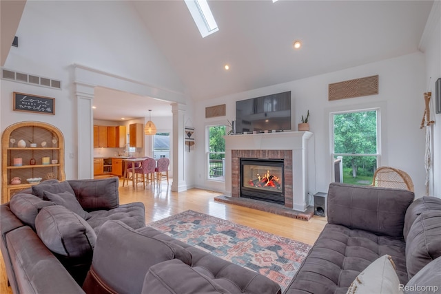 12462 Lillie Rd, Byron, MI 48418 - living area with light wood-style flooring, plenty of natural light, high vaulted ceiling, ornate columns, and a fireplace