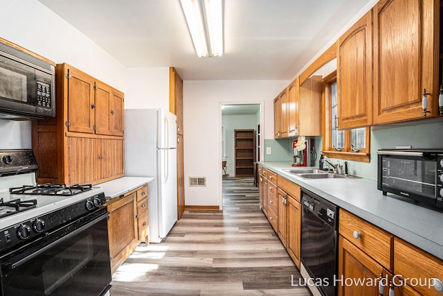 1124 Kusterer Dr NW, Grand Rapids, MI 49534 - kitchen featuring black appliances, light wood-style flooring, light countertops, and brown cabinetry