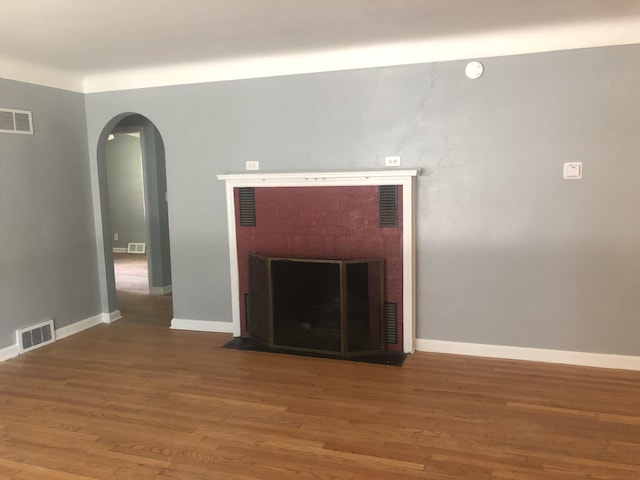 933 Westfall Ave, Kalamazoo, MI 49006 - unfurnished living room featuring a fireplace, arched walkways, and wood finished floors