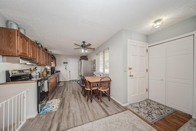 1361 Holmes Rd, Ypsilanti, MI 48198 - kitchen with stainless steel appliances, light wood-style flooring, brown cabinetry, a textured ceiling, and a ceiling fan