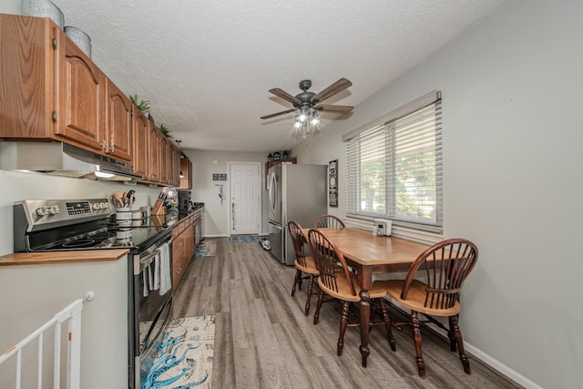 1361 Holmes Rd, Ypsilanti, MI 48198 - kitchen featuring stainless steel appliances, under cabinet range hood, light wood finished floors, a ceiling fan, and a textured ceiling