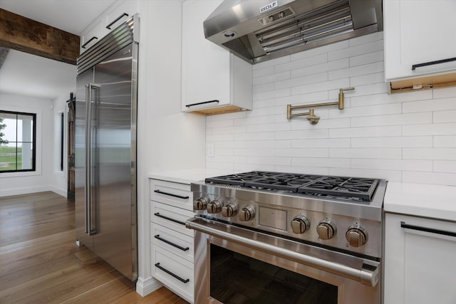7280 Austin Rd, Saline, MI 48176 - kitchen with premium appliances, ventilation hood, light countertops, and white cabinetry