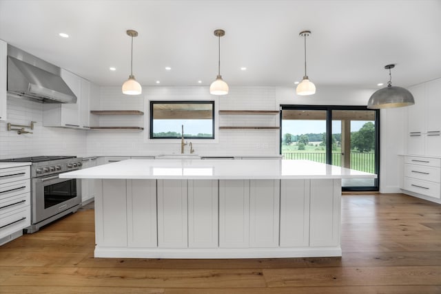 7280 Austin Rd, Saline, MI 48176 - kitchen with high end stainless steel range, open shelves, wall chimney exhaust hood, light countertops, and healthy amount of natural light
