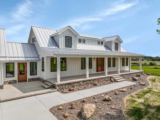 7280 Austin Rd, Saline, MI 48176 - modern farmhouse style home featuring a standing seam roof, a porch, board and batten siding, a metal roof, and stone siding