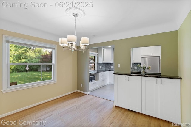 3603 Dukeshire Hwy, Royal Oak, MI 48073 - kitchen featuring refrigerator, stainless steel microwave, a chandelier, light wood finished floors, and backsplash