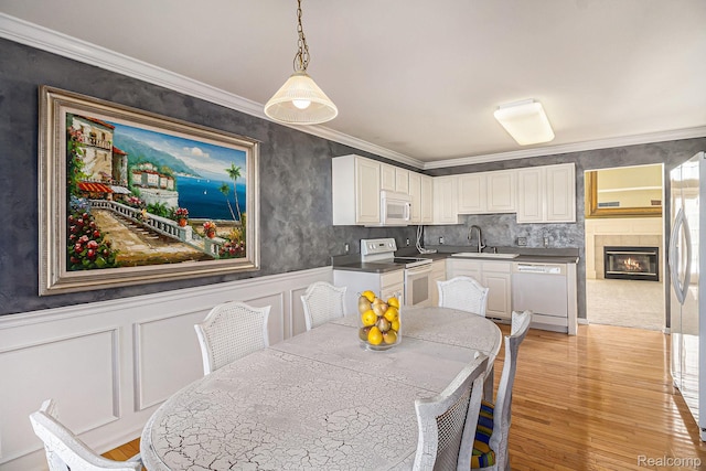 6438 Club Ct W, Grand Blanc, MI 48439 - dining room featuring light wood-type flooring, crown molding, a wainscoted wall, and a decorative wall