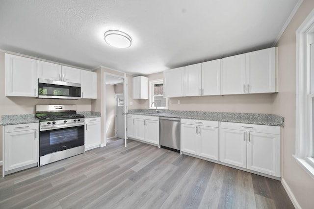 10620 Cady Rd, Jackson, MI 49201 - kitchen with stainless steel appliances, white cabinetry, light wood finished floors, and light stone countertops