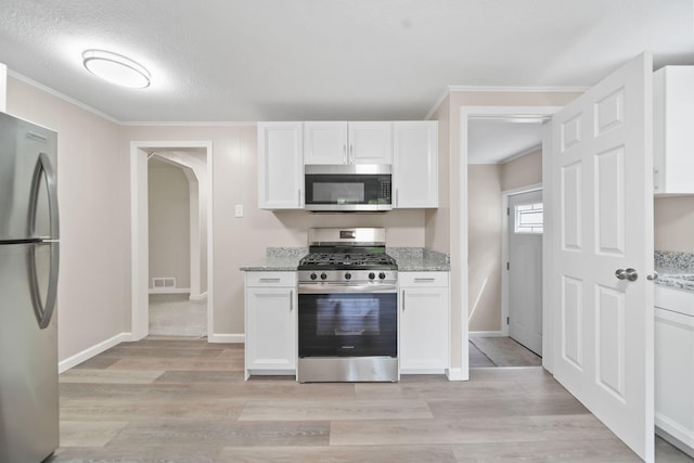 10620 Cady Rd, Jackson, MI 49201 - kitchen featuring appliances with stainless steel finishes, ornamental molding, white cabinetry, light wood-style floors, and light stone countertops