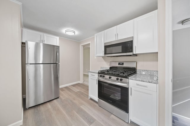10620 Cady Rd, Jackson, MI 49201 - kitchen featuring appliances with stainless steel finishes, white cabinets, light wood-style flooring, and light stone counters