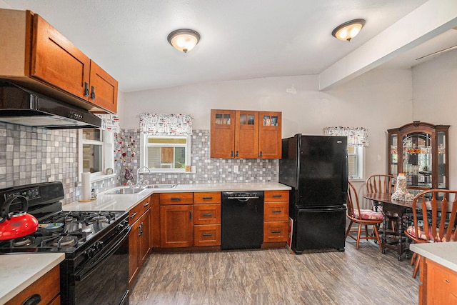 8828 Elm, Fremont, MI 49412 - kitchen with black appliances, under cabinet range hood, brown cabinetry, tasteful backsplash, and light countertops