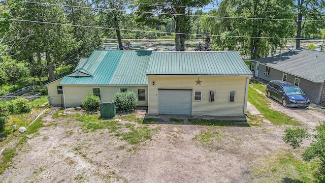 8828 Elm, Fremont, MI 49412 - view of side of home featuring a garage, dirt driveway, a metal roof, and view of wooded area