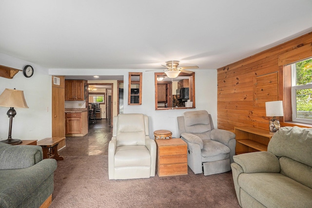 8828 Elm, Fremont, MI 49412 - living room with dark colored carpet, wooden walls, and a ceiling fan
