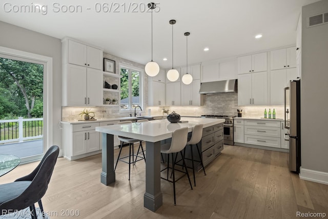 32575 Romsey Rd, Franklin, MI 48025 - kitchen with stainless steel appliances, exhaust hood, a breakfast bar, light wood-style flooring, and recessed lighting
