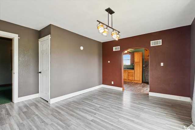 14211 Gilbert Rd, Waldron, MI 49288 - spare room featuring arched walkways and wood finished floors