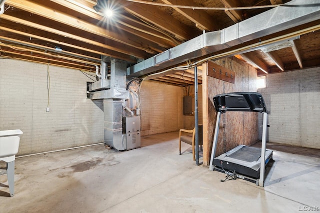 14211 Gilbert Rd, Waldron, MI 49288 - unfinished below grade area with electric panel, brick wall, and heating unit