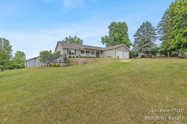 127 Hamilton Ln, Dowling, MI 49050 - view of front facade featuring a front yard, a trampoline, a garage, and covered porch