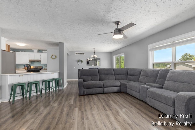 127 Hamilton Ln, Dowling, MI 49050 - living area featuring dark wood-style flooring, a ceiling fan, a chandelier, and a textured ceiling