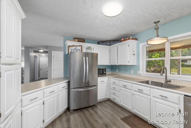 127 Hamilton Ln, Dowling, MI 49050 - kitchen featuring stainless steel appliances, a textured ceiling, white cabinets, light countertops, and dark wood-type flooring