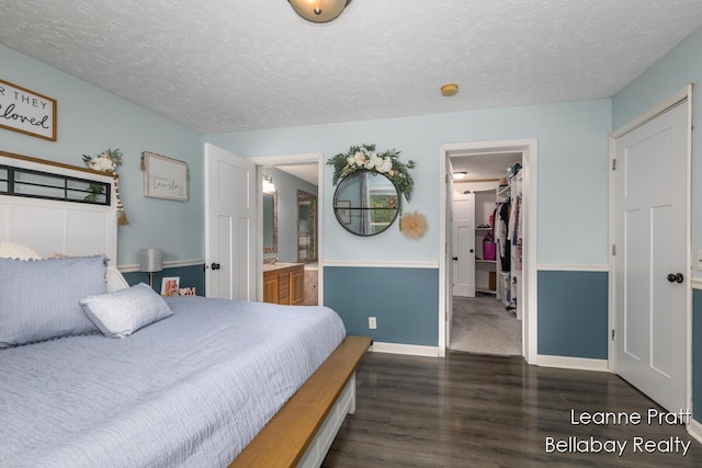 127 Hamilton Ln, Dowling, MI 49050 - bedroom with a textured ceiling, a walk in closet, dark wood finished floors, connected bathroom, and a closet