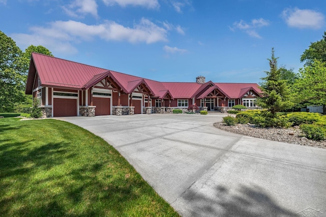199 E Brooks Rd, Midland, MI 48640 - view of front of house featuring a chimney, a front yard, stone siding, a metal roof, and driveway