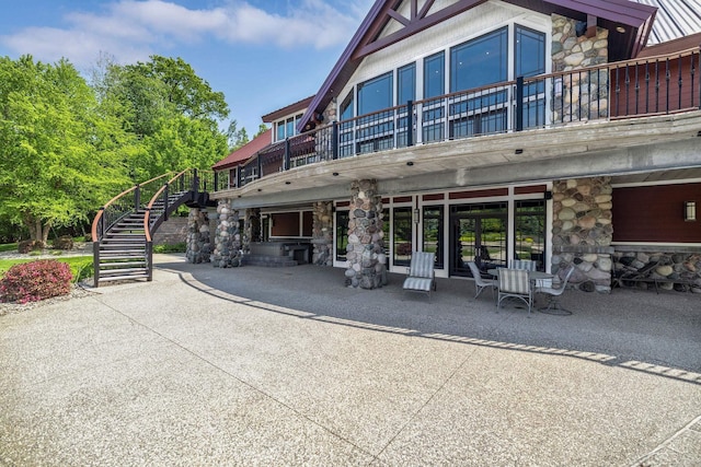 199 E Brooks Rd, Midland, MI 48640 - back of house with stone siding, stairs, a balcony, and a patio