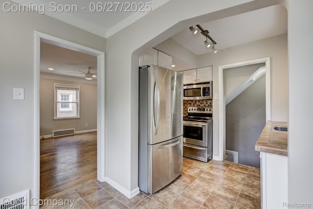 830 W Hazelhurst St, Ferndale, MI 48220 - kitchen featuring stainless steel appliances, white cabinets, decorative backsplash, and a ceiling fan