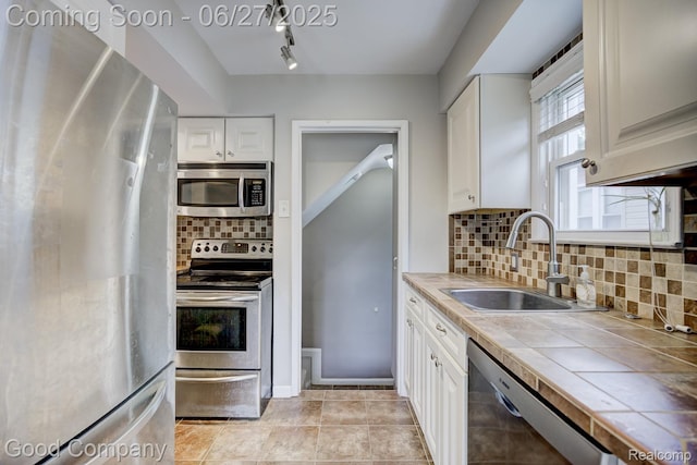 830 W Hazelhurst St, Ferndale, MI 48220 - kitchen featuring stainless steel appliances, tile countertops, white cabinetry, tasteful backsplash, and track lighting