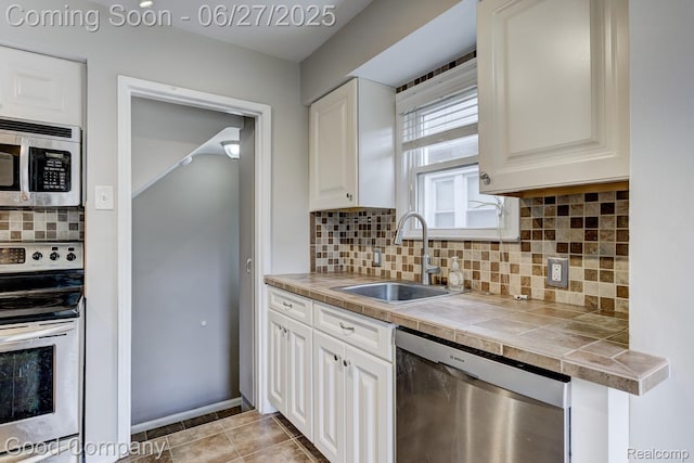 830 W Hazelhurst St, Ferndale, MI 48220 - kitchen featuring appliances with stainless steel finishes, tile counters, white cabinets, decorative backsplash, and light tile patterned floors