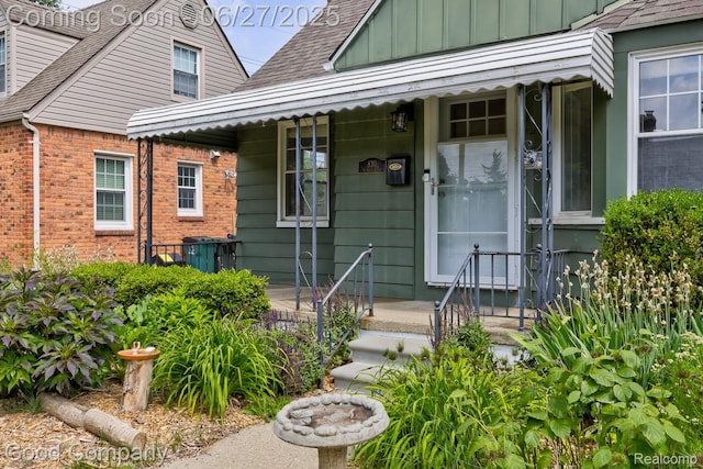 830 W Hazelhurst St, Ferndale, MI 48220 - view of exterior entry with a shingled roof, board and batten siding, brick siding, and a porch