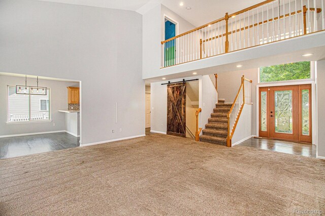 11275 Grand Oaks Dr, Clio, MI 48420 - unfurnished living room featuring a barn door, a high ceiling, stairway, carpet, and recessed lighting