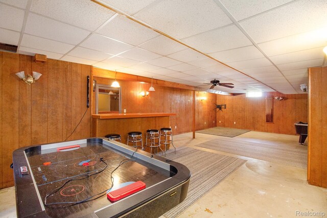 11275 Grand Oaks Dr, Clio, MI 48420 - game room with a bar, wooden walls, a paneled ceiling, and concrete floors