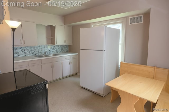 2614 Trumbull Ave, Flint, MI 48504 - kitchen featuring freestanding refrigerator, light flooring, backsplash, black range with electric stovetop, and white cabinetry