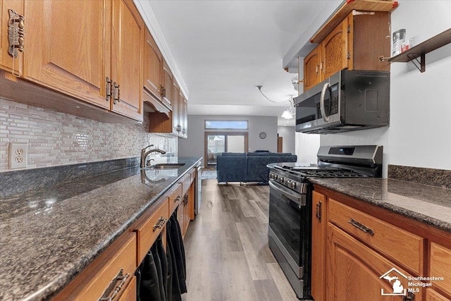 1617 Davis St, Wyandotte, MI 48192 - kitchen featuring appliances with stainless steel finishes, light wood-style flooring, brown cabinets, backsplash, and open floor plan